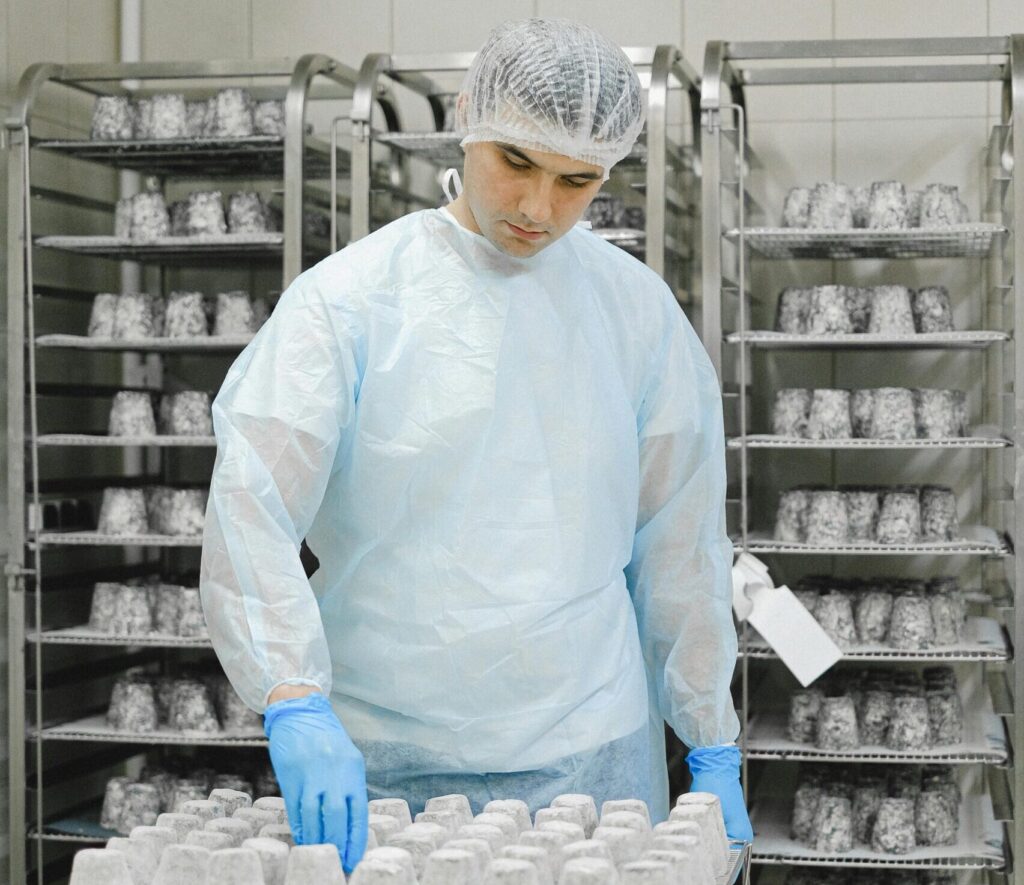 A worker in hygienic clothing handling food storage in a production facility.